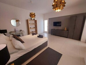 A modern bedroom with a bed, bedside table, and a TV mounted on the wall. - Sliema- Room in Historic Palazzo (Tas-Sliema)