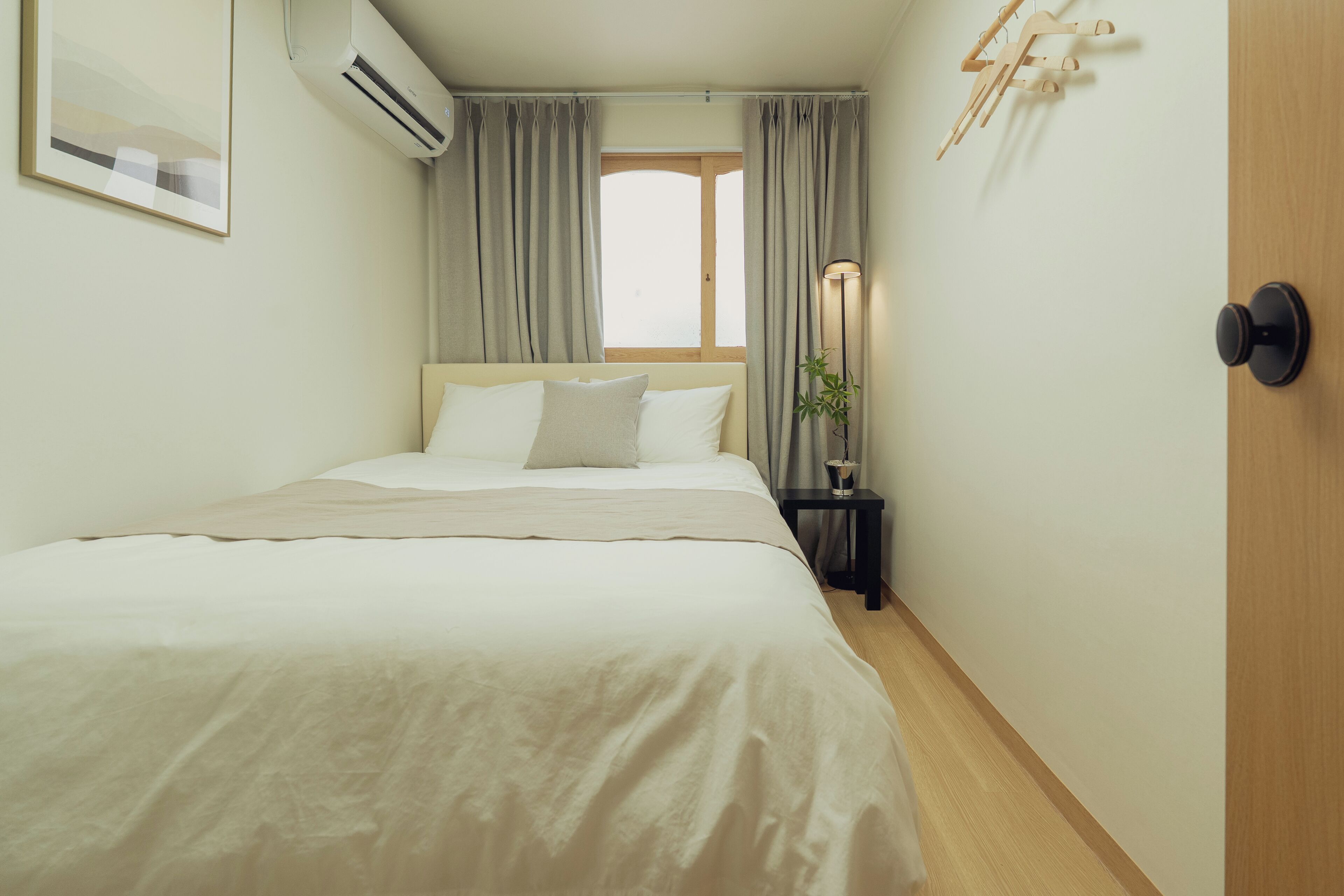 A bedroom with a bed, a nightstand, a lamp, and a window with curtains.
