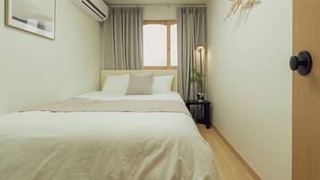 A bedroom with a bed, a nightstand, a lamp, and a window with curtains.