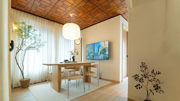 A dining area with a wooden table, chairs, a potted plant, and a television on the wall. - 5MINS SEOUL STATION-3BR FAMILY STAY WITH PATIO (Seoul)