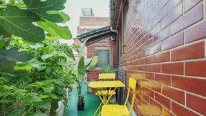 A narrow alley with a brick wall, a potted plant, and yellow folding chairs. - 5MINS SEOUL STATION-3BR FAMILY STAY WITH PATIO (Seoul)