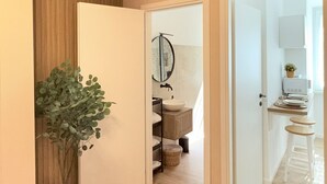 A hallway with a plant, a mirror, a sink, and a kitchen area with stools. - Santa Maria Apartment - Rome - 15 minutes from the Colosseum (Roma)