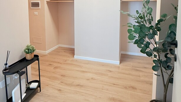 A spacious room with wooden flooring, built-in shelving, a small table with a plant, and a ceiling light fixture. - Santa Maria Apartment - Rome - 15 minutes from the Colosseum (Roma)