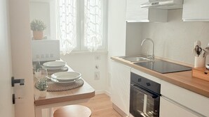 A modern kitchen with white cabinets, a wooden countertop, a sink, and a window with patterned curtains. - Santa Maria Apartment - Rome - 15 minutes from the Colosseum (Roma)