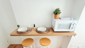 A kitchen with a microwave, two stools, and a small potted plant on a shelf. - Santa Maria Apartment - Rome - 15 minutes from the Colosseum (Roma)