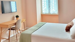 A bedroom with a bed, a desk, a chair, a television, and an air conditioning unit. - Santa Maria Apartment - Rome - 15 minutes from the Colosseum (Roma)