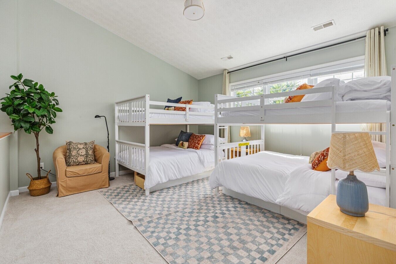 Ein Zimmer mit Etagenbetten, einem Blumentopf, einem Stuhl und einer Lampe.