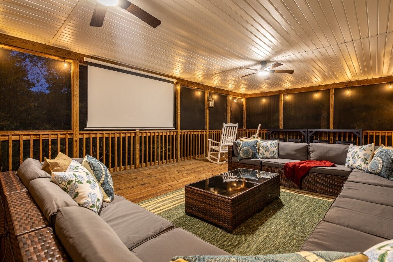 Ein Open-Air-Kino mit großer Leinwand, bequemen Sitzgelegenheiten und einem Deckenventilator.