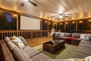 Ein Open-Air-Kino mit großer Leinwand, bequemen Sitzgelegenheiten und einem Deckenventilator.