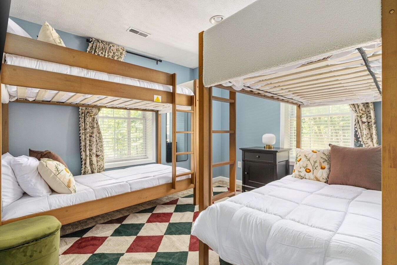 A bunk bed room with a checkered floor, a desk, and a ladder.
