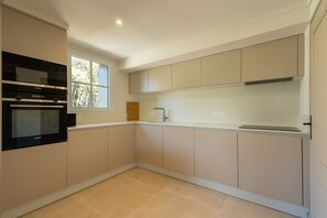 A modern kitchen with built-in appliances, a window, and light-colored cabinetry. - La Pinède du Ferret - Climatisée et plage à 500 m (Lège-Cap-Ferret)