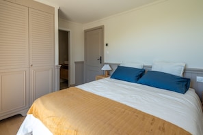 A bedroom with a bed, a wardrobe, a nightstand, and a door to a hallway. - La Pinède du Ferret - Climatisée et plage à 500 m (Lège-Cap-Ferret)