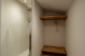 A shower area with a glass door, a wooden shelf, and a ceiling-mounted showerhead. - La Pinède du Ferret - Climatisée et plage à 500 m (Lège-Cap-Ferret)