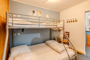 A bunk bed with a ladder, a chair, and a small table in a room with a wooden ceiling and light blue walls. - Les Ambrunes - Station de ski accessible à pied (Châtel)