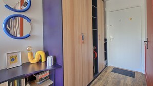 Een hal met een houten garderobe, een spiegel, een lijst met een afbeelding en een tafeltje met decoratieve objecten.