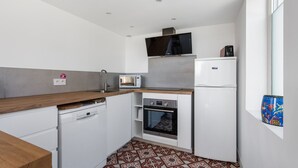 Eine kleine Küche mit Geschirrspüler, Mikrowelle, Backofen und Kühlschrank.