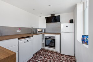 Eine kleine Küche mit Geschirrspüler, Mikrowelle, Backofen und Kühlschrank.
