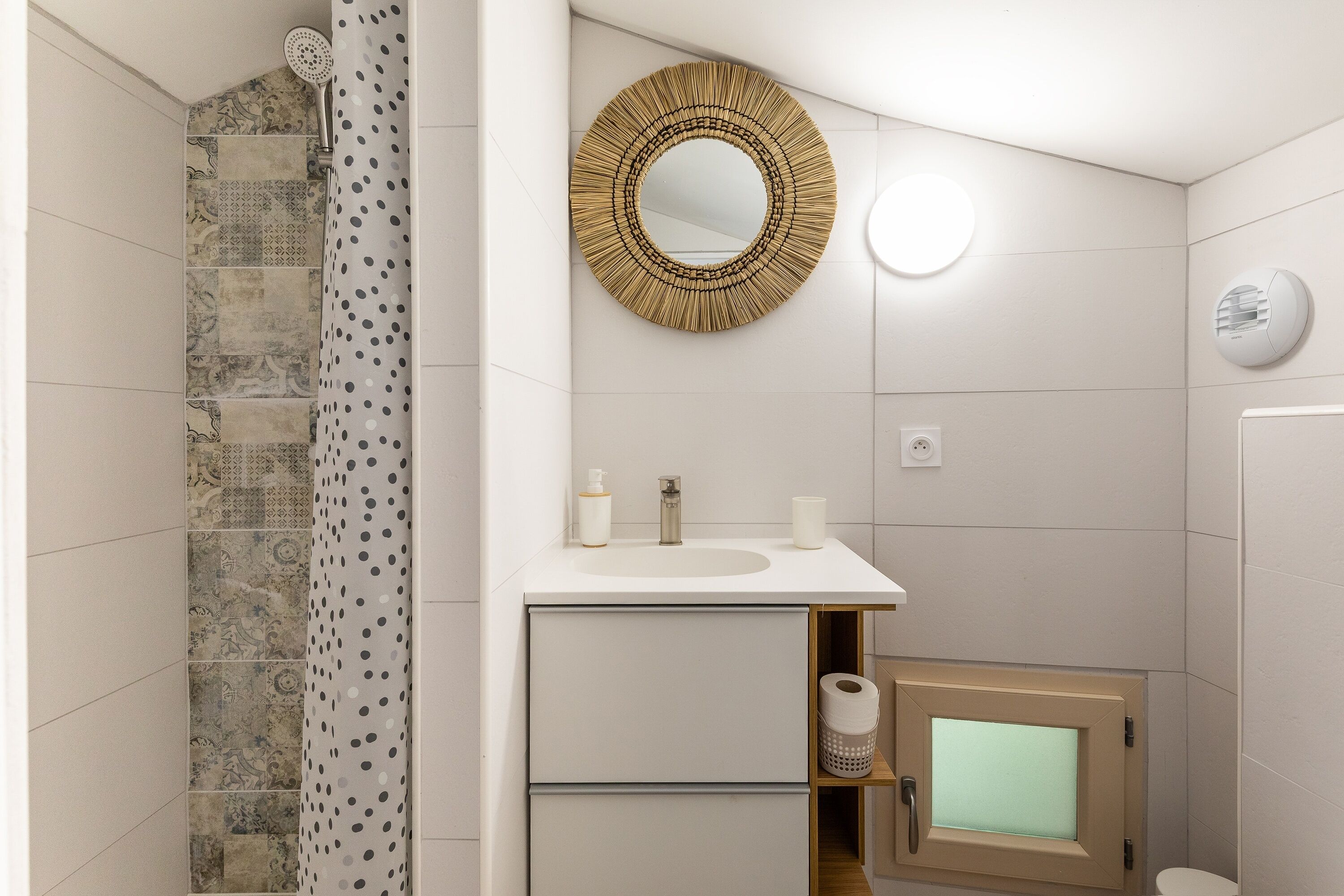 Ein Badezimmer mit Dusche, Waschbecken mit Spiegel und Toilette.