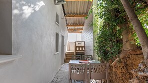 Eine schmale Außenpatio mit Tisch und Stühlen, einer Holztreppe und einer mit Grünpflanzen bewachsenen Wand.