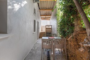 Eine schmale Außenpatio mit Tisch und Stühlen, einer Holztreppe und einer mit Grünpflanzen bewachsenen Wand.
