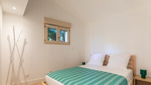 Ein Schlafzimmer mit einem Bett, einem Fenster, einem Nachttisch und einer Stehlampe.