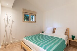 Ein Schlafzimmer mit einem Bett, einem Fenster, einem Nachttisch und einer Stehlampe.
