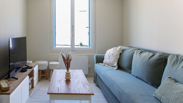 Ein Wohnzimmer mit Fernseher, Couch, Holztisch und Fenster.