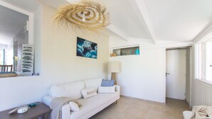 Ein Zimmer mit einem weißen Sofa, einer Lampe, einem Gemälde und einem Deckenventilator.