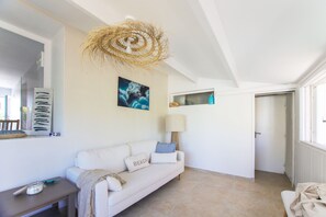 A room with a white sofa, a lamp, a painting, and a ceiling fan. - Villa Trafal - Proche plage (Saint-Michel-en-l'Herm)
