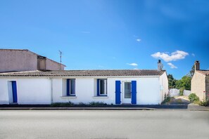 A white building with blue shutters, a tiled roof, and a clear blue sky. - Villa Trafal - Proche plage (Saint-Michel-en-l'Herm)