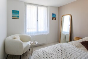 A bedroom with a bed, a chair, a small table, a mirror, and two posters on the wall. - Villa Trafal - Proche plage (Saint-Michel-en-l'Herm)