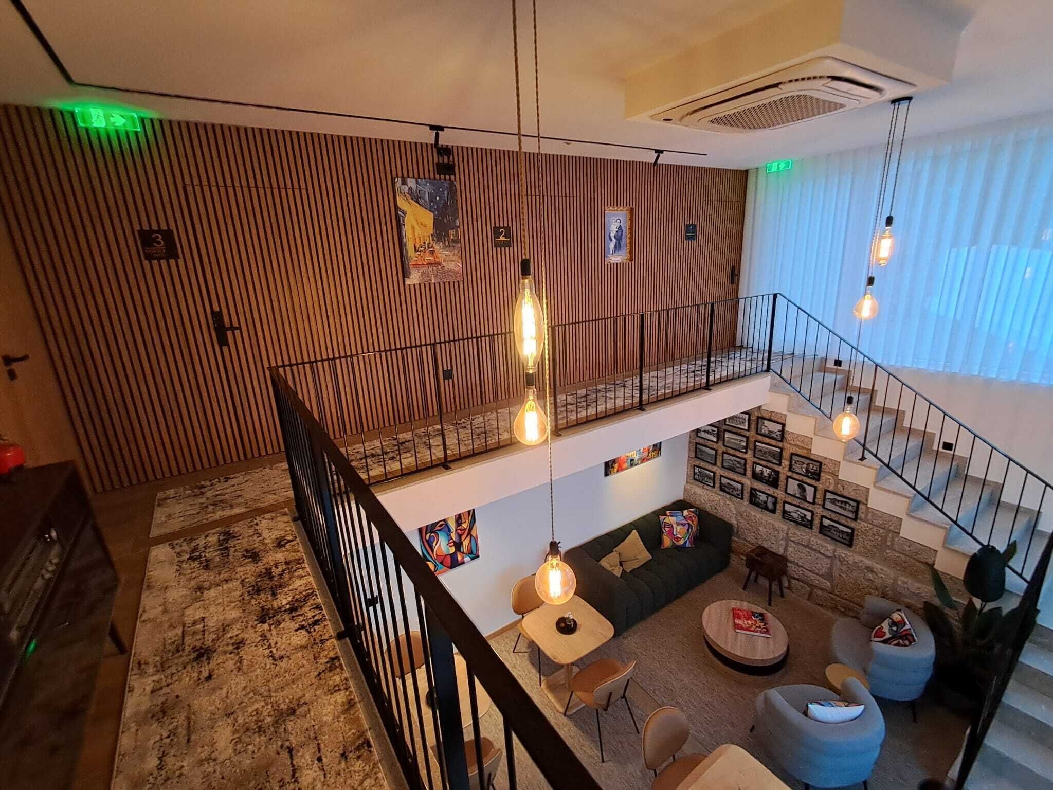 Un intérieur à plusieurs niveaux, avec un escalier, un coin salon et des luminaires suspendus.