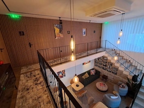 A multi-level interior with a staircase, seating area, and hanging pendant lights.