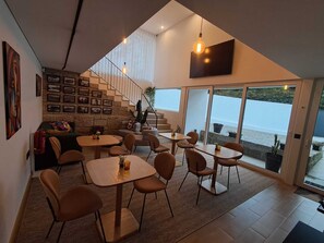 A modern interior with a staircase, dining area, and large sliding glass doors leading to a balcony with a view. - Casa de Santo António - Suite 1 (Marco de Canaveses)