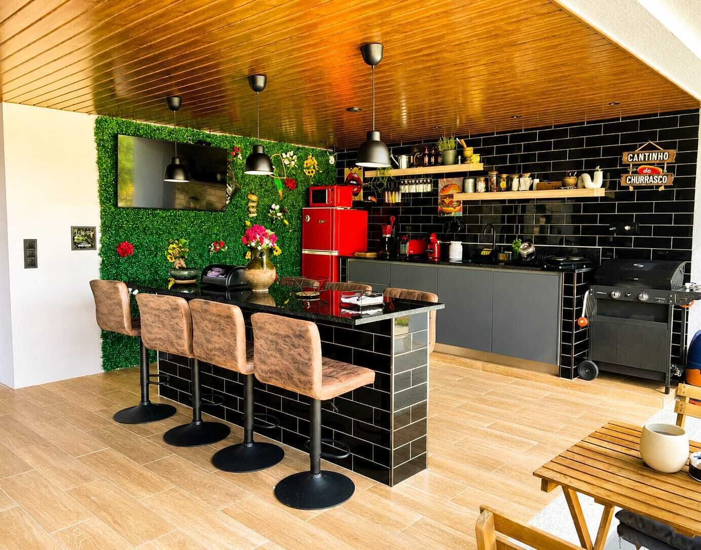 A modern kitchen with a bar area, wooden flooring, and a green wall with plants.