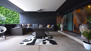 Un área de estar exterior moderna con un sofá modular, una mesa de centro y almohadones decorativos.