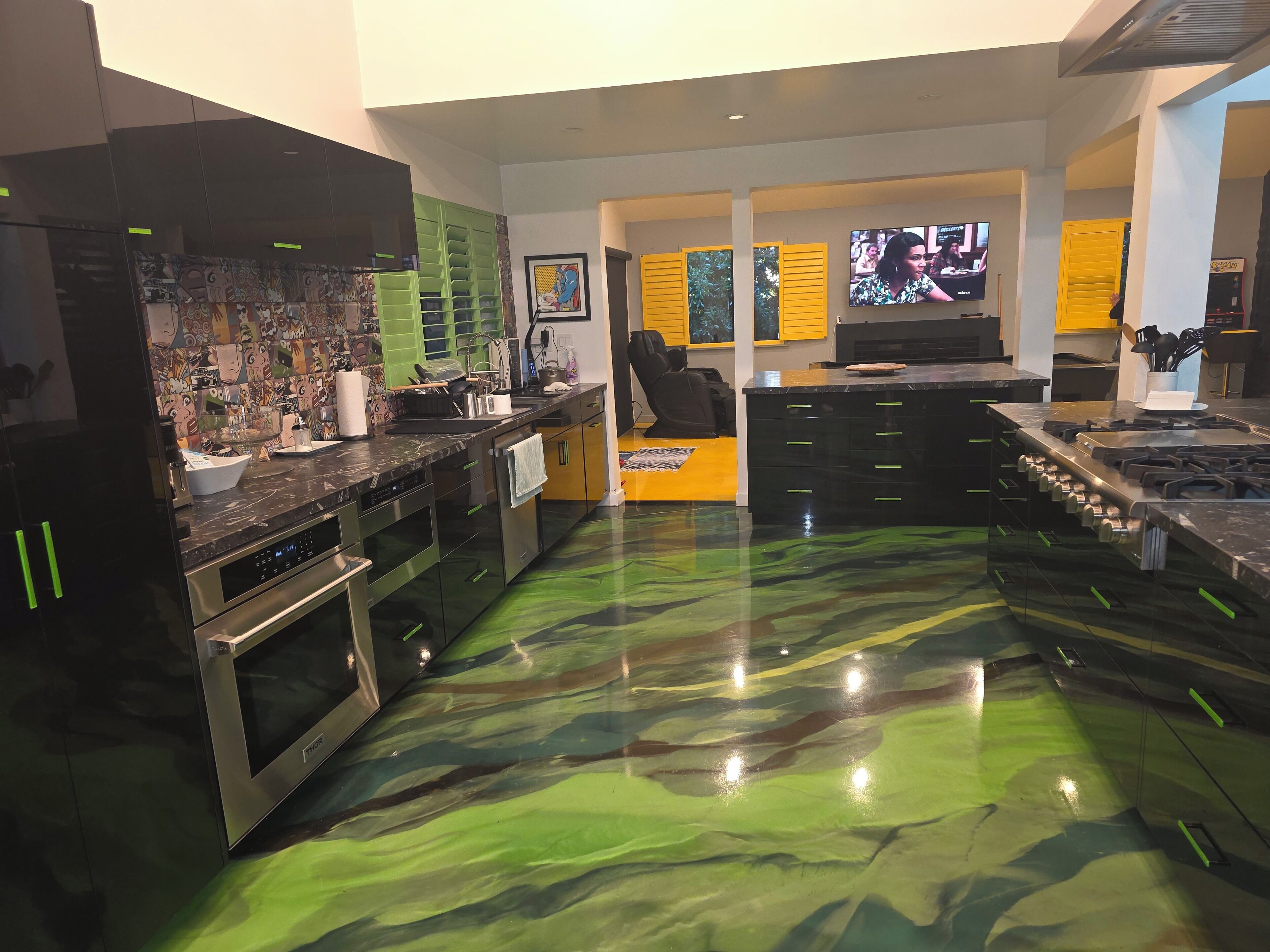 Een moderne keuken met roestvrijstalen apparatuur, een groot kookeiland en een bijzondere vloer van groene marmer.