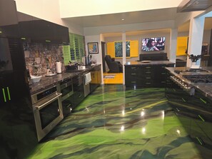 A modern kitchen with stainless steel appliances, a large island, and a unique green marble floor. - Spacious private Oasis (Los Angeles)