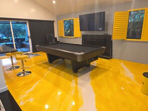 A pool table in a room with yellow flooring, a TV mounted on the wall, and a fireplace. - Spacious private Oasis (Los Angeles)