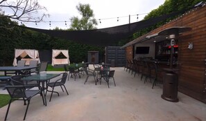 An outdoor patio area with tables and chairs, a bar area, and a covered seating area. - Spacious private Oasis (Los Angeles)