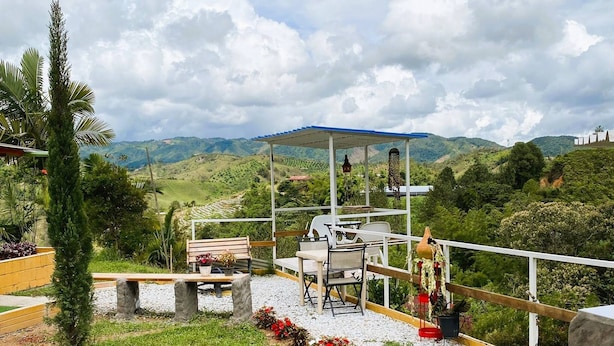 A terrace with outdoor seating, a view of the hills, and a covered area with a table and chairs. - Nomad Nest Near Guatapé Jacuzzi Turkish Wifi-full (El Peñol)