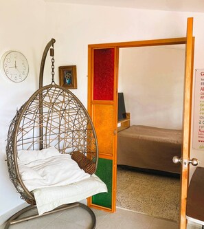 A room with a hanging chair, a bed, a wall clock, and a door with a red panel. - Nomad Nest Near Guatapé Jacuzzi Turkish Wifi-full (El Peñol)