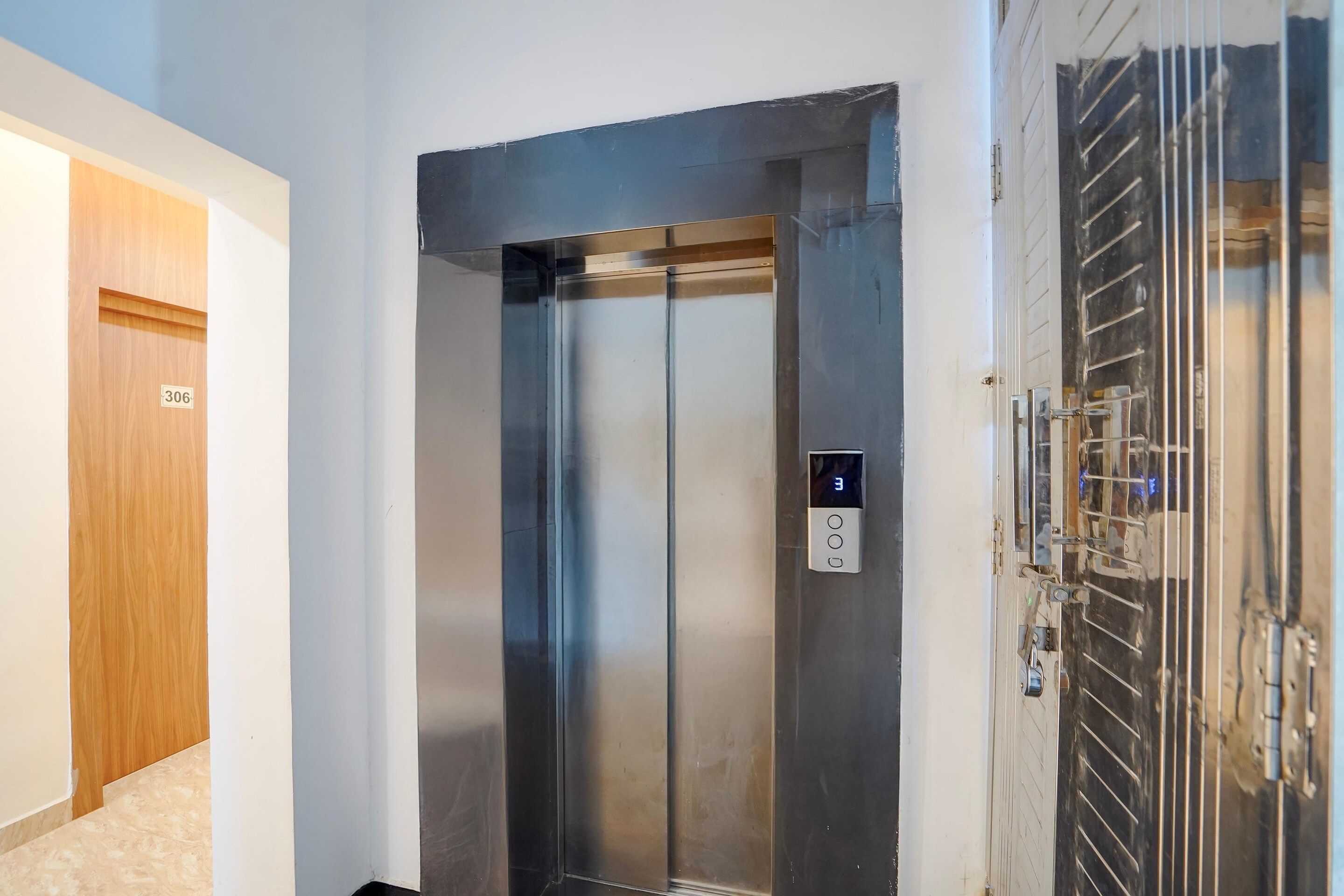 Un ascensor con pantalla digital, una puerta con placa de identificación y una reja metálica.