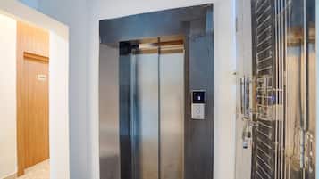 Un ascensor con pantalla digital, una puerta con placa de identificación y una reja metálica.