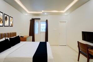 Una habitación de hotel con una cama, un escritorio, un televisor y una puerta.