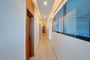 A corridor with a wooden door labeled '03' and a glass wall with a seating area.