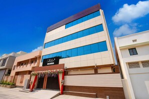 A multi-story building with a modern architectural design, featuring a prominent entrance with a sign that reads 'Collection' and 'Oyo-Serviced'. - Deluxe Aarunya Residency And Banquets (Patna)