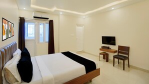 Ein Hotelzimmer mit einem Bett, einem Fernseher, einem Schreibtisch und einem Sessel.