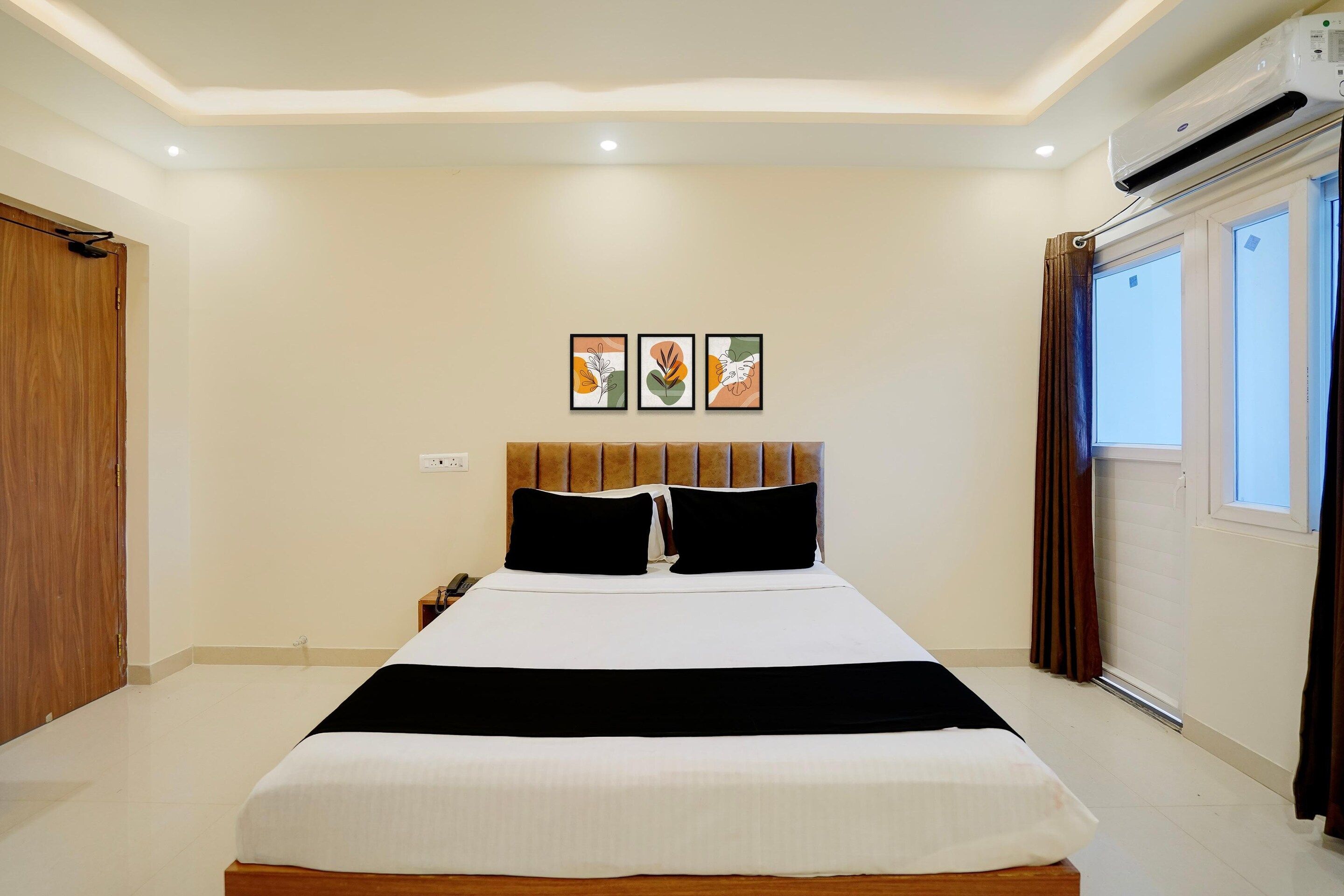 Una habitación de hotel con una cama, una mesita de noche, un teléfono y una ventana con cortinas.