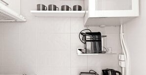 Eine Küche mit Kaffeemaschine, Toaster und einer Ablage für Tassen.